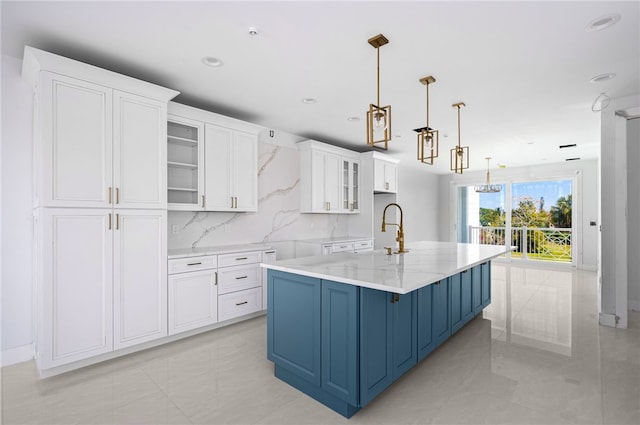 kitchen featuring white cabinetry, blue cabinets, a large island, glass insert cabinets, and decorative light fixtures