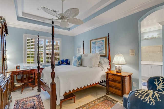 bedroom with a raised ceiling, crown molding, light tile patterned floors, and ensuite bath