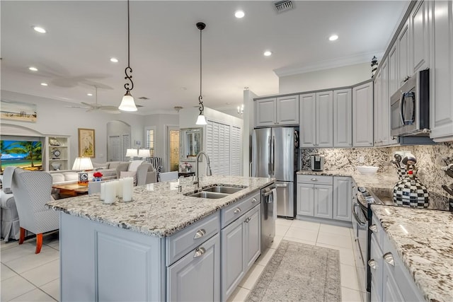 kitchen featuring sink, gray cabinetry, hanging light fixtures, a kitchen island with sink, and stainless steel appliances