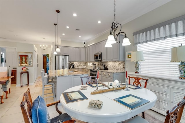 dining area featuring sink, a notable chandelier, ornamental molding, and light tile patterned flooring