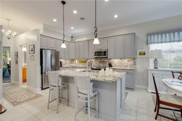 kitchen with stainless steel appliances, gray cabinets, and a center island with sink