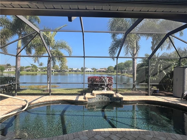 outdoor pool with glass enclosure, a water view, and a patio area