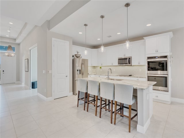 kitchen featuring decorative light fixtures, stainless steel appliances, and a center island with sink