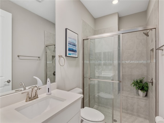 bathroom with vanity, toilet, and a shower with shower door