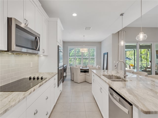 kitchen with appliances with stainless steel finishes, decorative backsplash, white cabinets, light stone counters, and sink