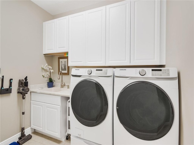 laundry area featuring light tile patterned floors, cabinets, washer and dryer, and sink