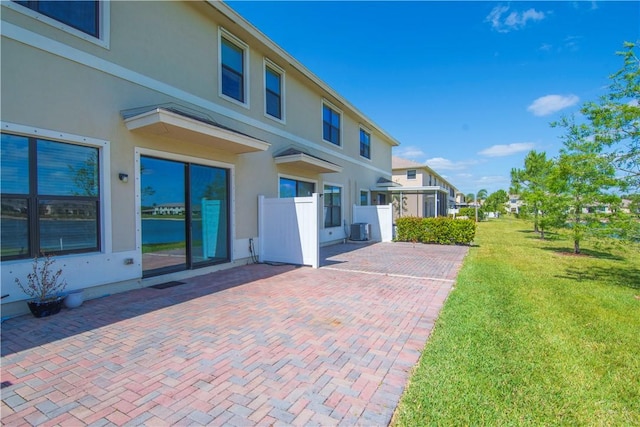10008 W Villa Cir Unit 10008, Vero Beach, FL 32966 - back of property featuring fence, a patio, stucco siding, central AC unit, and a yard