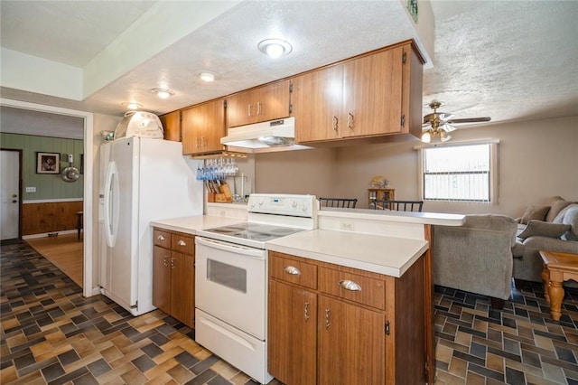 6001 Palm Dr, Fort Pierce, FL 34982 - kitchen with white appliances, under cabinet range hood, a peninsula, light countertops, and wooden walls