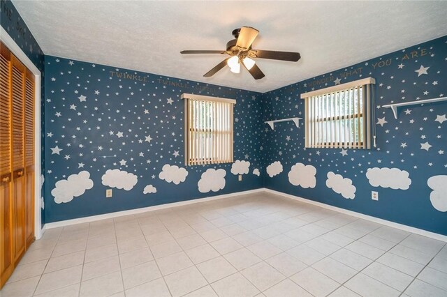 6001 Palm Dr, Fort Pierce, FL 34982 - empty room with healthy amount of natural light, ceiling fan, a textured ceiling, tile patterned flooring, and baseboards