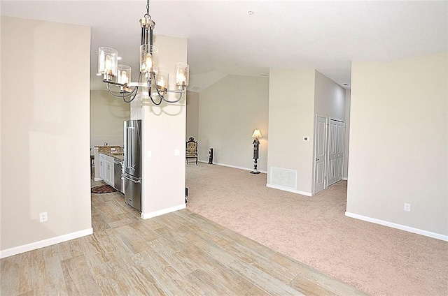 3951 Playa Del Sol Dr Unit 201, Rockledge, FL 32955 - empty room featuring an inviting chandelier, visible vents, baseboards, light wood-type flooring, and vaulted ceiling