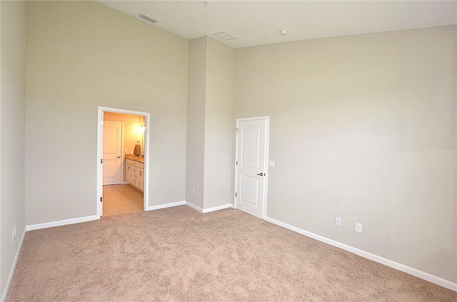 3951 Playa Del Sol Dr Unit 201, Rockledge, FL 32955 - unfurnished bedroom featuring visible vents, light carpet, baseboards, a high ceiling, and connected bathroom