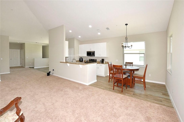 3951 Playa Del Sol Dr Unit 201, Rockledge, FL 32955 - kitchen with baseboards, stainless steel microwave, and light carpet