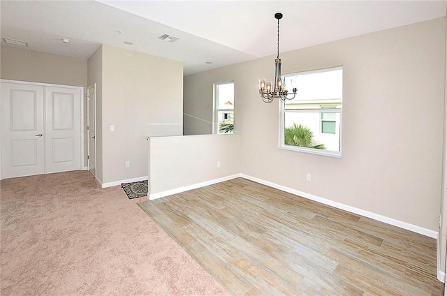 3951 Playa Del Sol Dr Unit 201, Rockledge, FL 32955 - unfurnished room with baseboards, a notable chandelier, light wood-type flooring, and visible vents