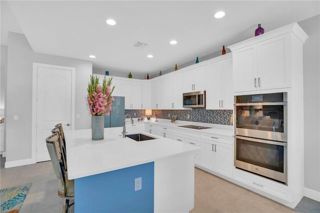 kitchen featuring white cabinets, sink, an island with sink, and stainless steel appliances