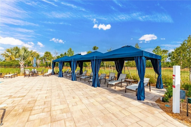 view of community featuring fence, a gazebo, and a patio area