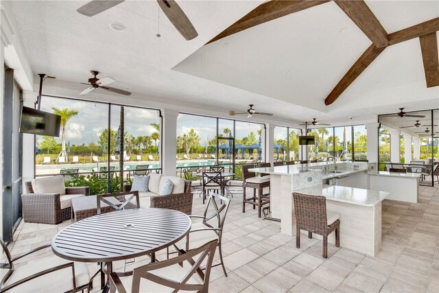 sunroom / solarium with beamed ceiling, a ceiling fan, and outdoor wet bar