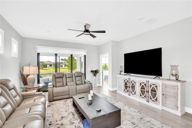 living area featuring baseboards, visible vents, ceiling fan, and wood finished floors