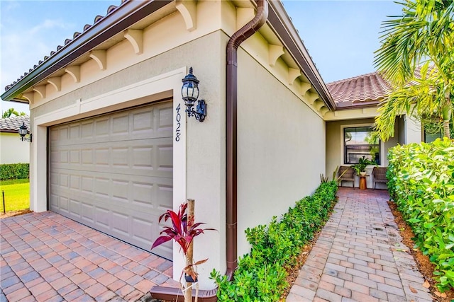 view of side of home featuring stucco siding, driveway, and a garage