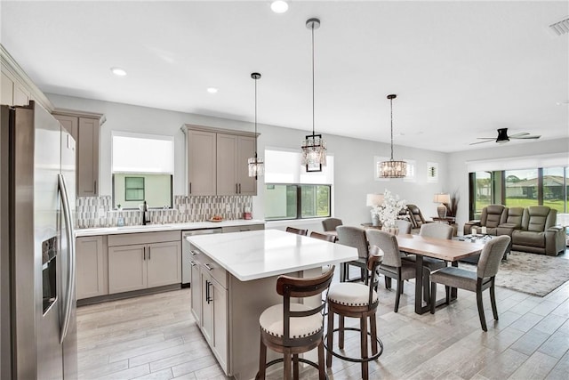 kitchen with a sink, stainless steel appliances, gray cabinets, a healthy amount of sunlight, and light wood finished floors