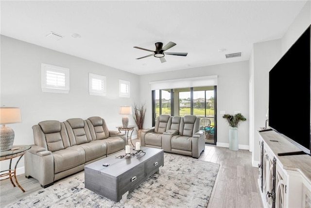 living room with light wood finished floors, baseboards, a ceiling fan, and visible vents