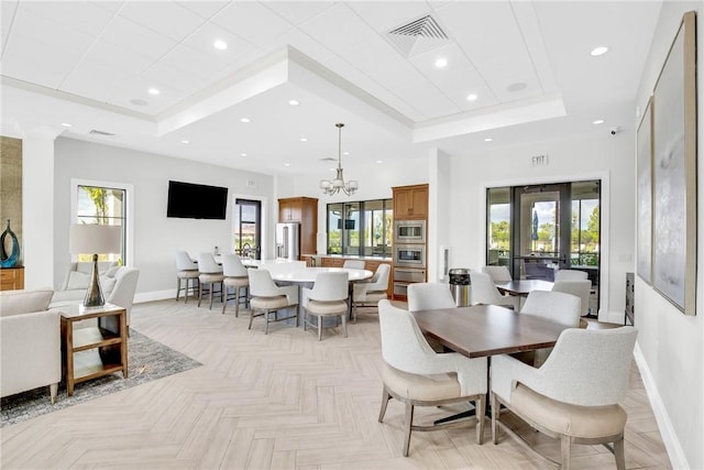 dining area with a tray ceiling, a wealth of natural light, visible vents, and baseboards