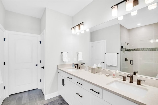 bathroom featuring double vanity, baseboards, a stall shower, and a sink