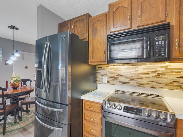 kitchen featuring tasteful backsplash, decorative light fixtures, stainless steel appliances, and a textured ceiling