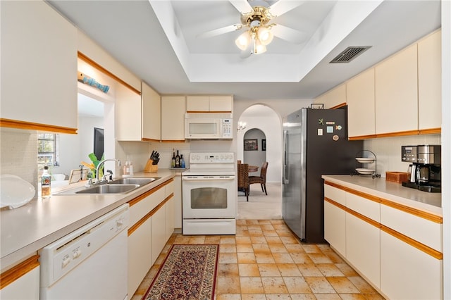 kitchen with sink, ceiling fan, backsplash, a tray ceiling, and white appliances