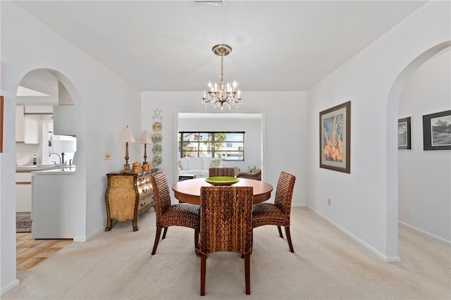 dining space with light colored carpet and a chandelier