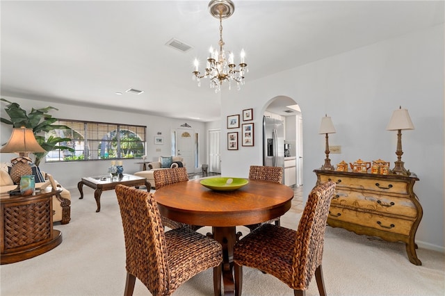 carpeted dining area with a chandelier