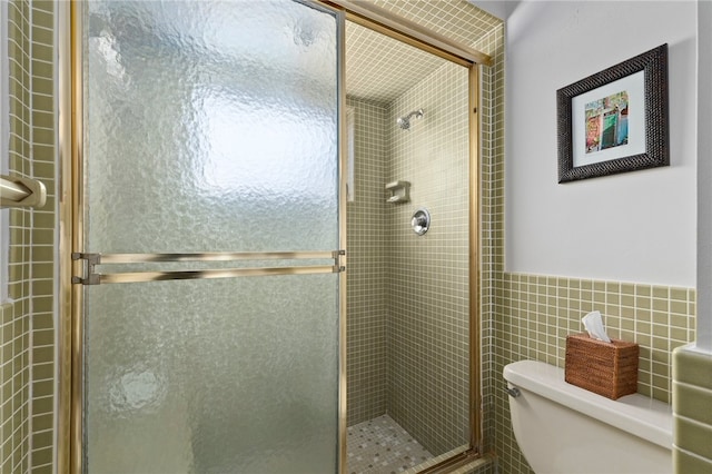 bathroom with tile walls, walk in shower, and toilet