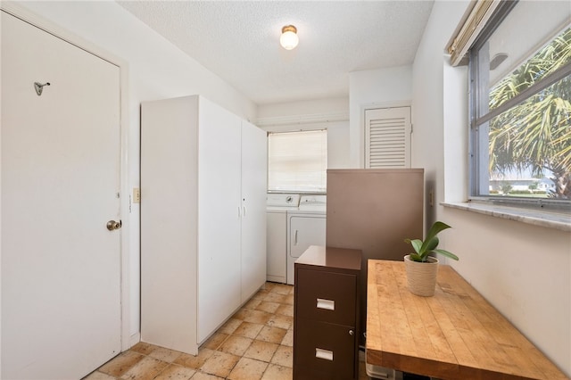 bathroom with a textured ceiling, washing machine and dryer, and a healthy amount of sunlight