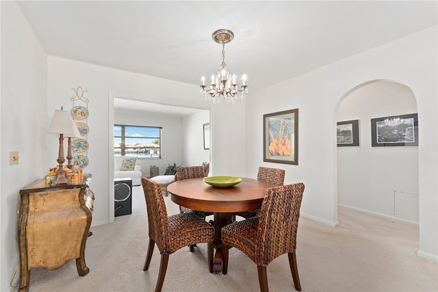 dining space featuring light carpet and a notable chandelier