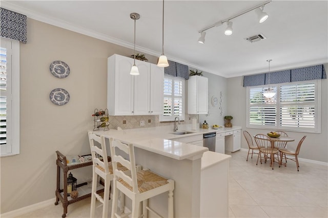 6341 Astor Pl, Vero Beach, FL 32966 - kitchen with stainless steel dishwasher, a sink, white cabinets, light countertops, and a kitchen breakfast bar
