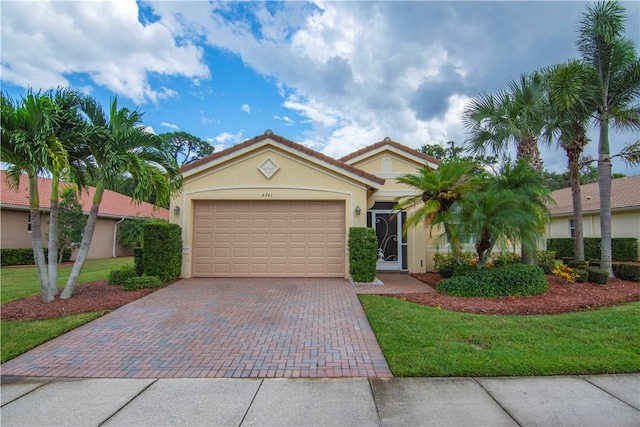 6341 Astor Pl, Vero Beach, FL 32966 - view of front of house featuring stucco siding, decorative driveway, an attached garage, a front yard, and a tiled roof
