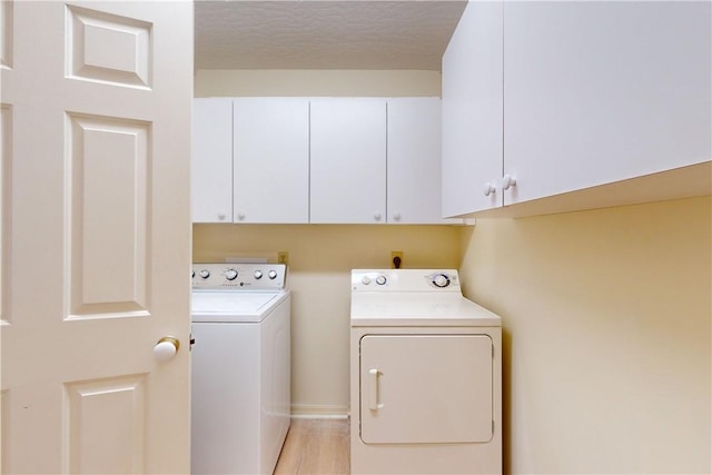 laundry area featuring cabinets, light hardwood / wood-style flooring, washer and dryer, and a textured ceiling