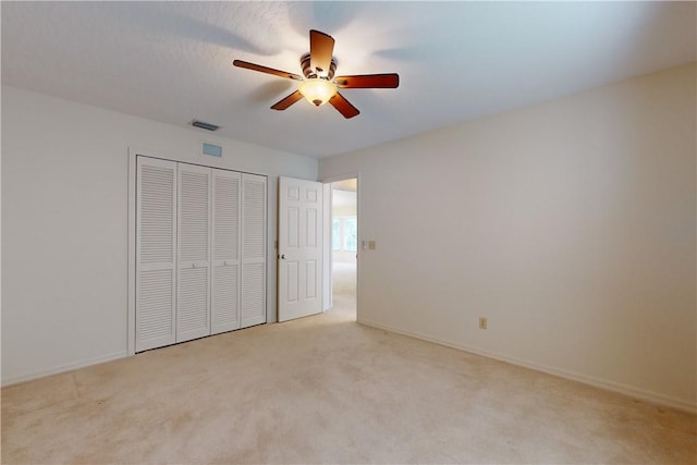 unfurnished bedroom with light colored carpet, a closet, and ceiling fan