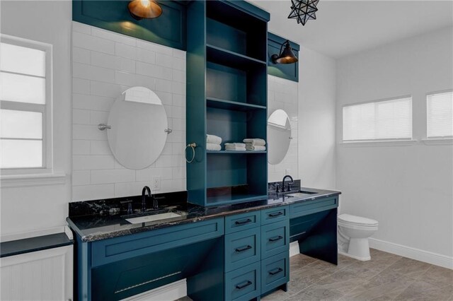 bathroom with decorative backsplash, vanity, toilet, and a healthy amount of sunlight