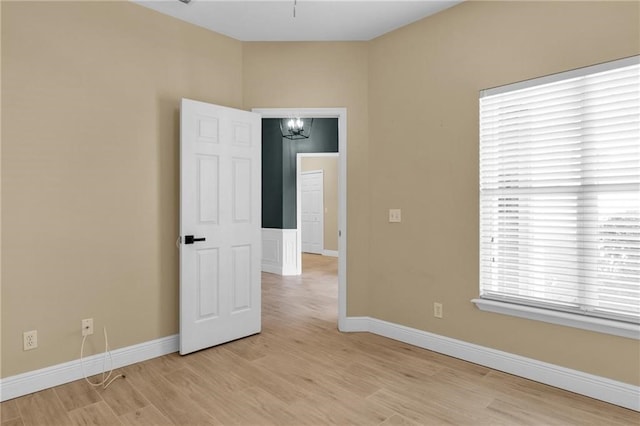 unfurnished room with light hardwood / wood-style flooring and an inviting chandelier