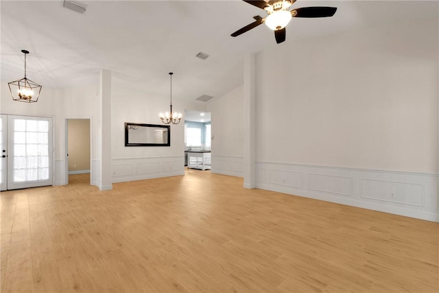 unfurnished living room with ceiling fan with notable chandelier, french doors, and light hardwood / wood-style flooring