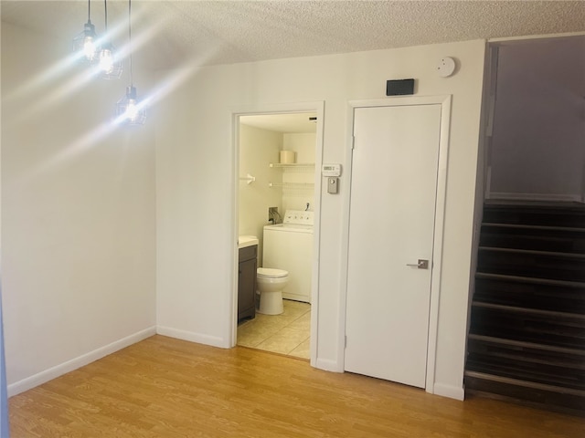 interior space with vanity, hardwood / wood-style flooring, toilet, separate washer and dryer, and a textured ceiling