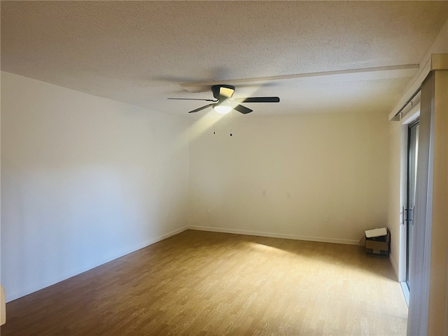 empty room with ceiling fan, a textured ceiling, and light hardwood / wood-style flooring