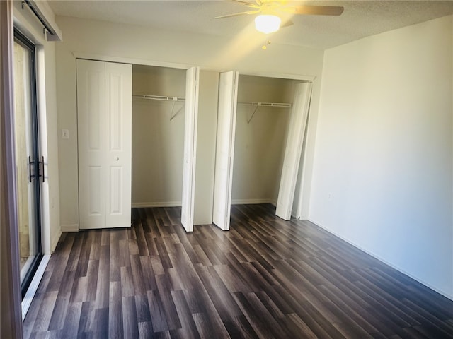 unfurnished bedroom featuring a textured ceiling, multiple closets, ceiling fan, and dark hardwood / wood-style floors