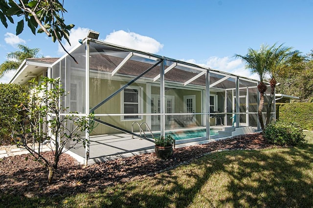 rear view of property with a lawn, glass enclosure, and a patio area