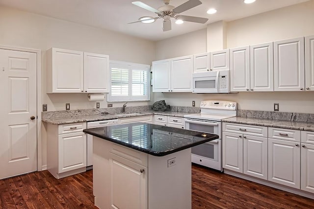 kitchen with white cabinets, a kitchen island, and white appliances