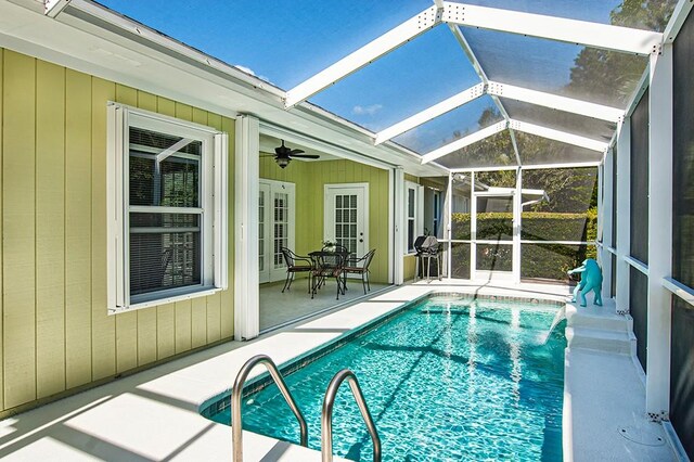 view of pool with a patio, glass enclosure, and ceiling fan