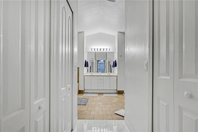 bathroom featuring vanity, lofted ceiling, tile patterned floors, and a textured ceiling