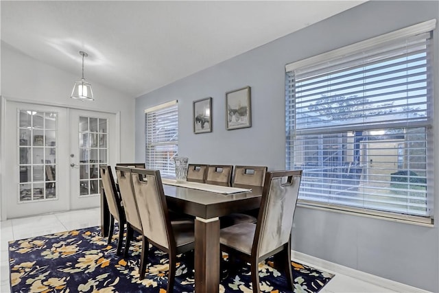 dining room with lofted ceiling, a healthy amount of sunlight, light tile patterned floors, and french doors