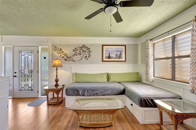 1805 15th St SW, Vero Beach, FL 32962 - bedroom featuring a textured ceiling, light wood finished floors, ceiling fan, a decorative wall, and a wainscoted wall