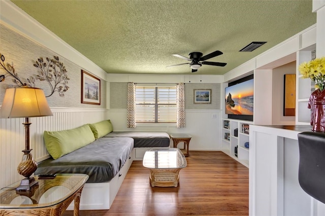 1805 15th St SW, Vero Beach, FL 32962 - living room featuring wood finished floors, a ceiling fan, a wainscoted wall, a textured ceiling, and visible vents